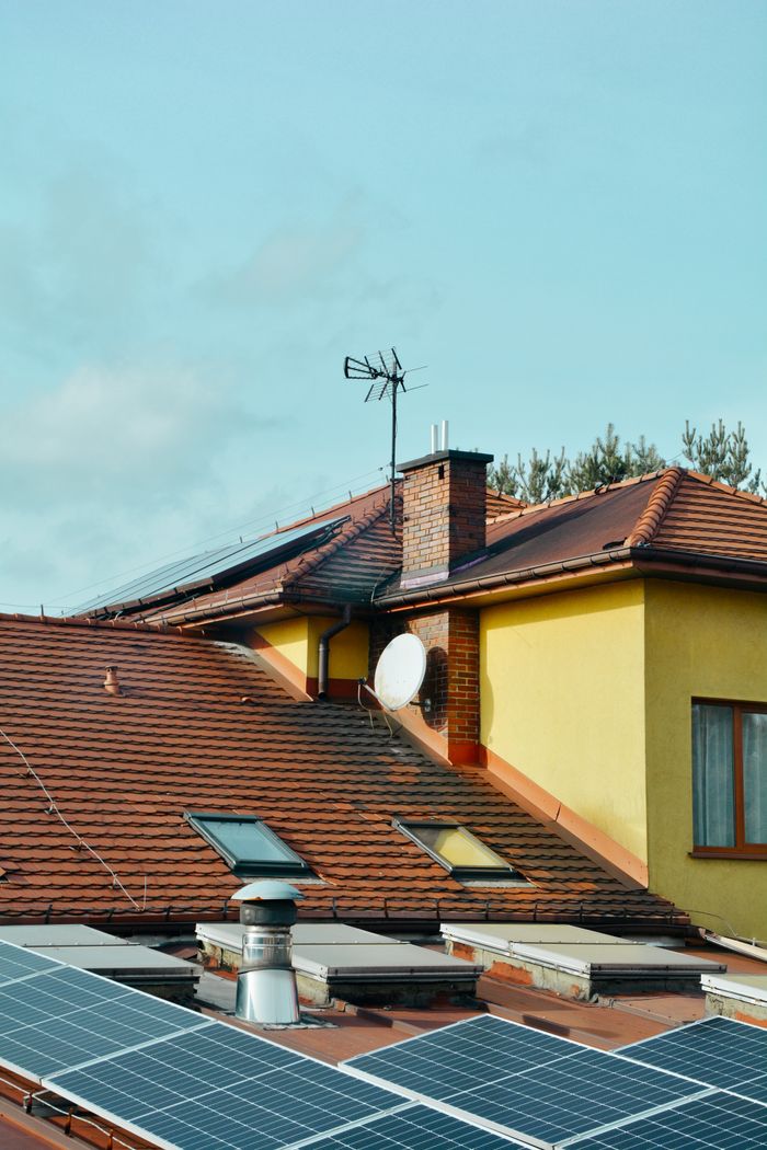 Home Yellow building with solar panels and antennas on rooftop in Poland. Eco-friendly technology.